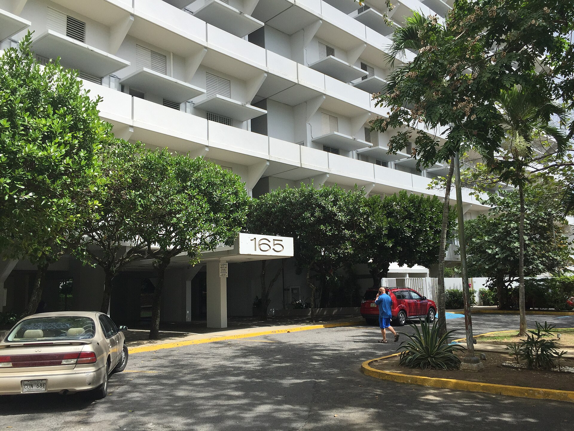 Entrada de un condominio con balcones y vegetación tropical en Hato Rey